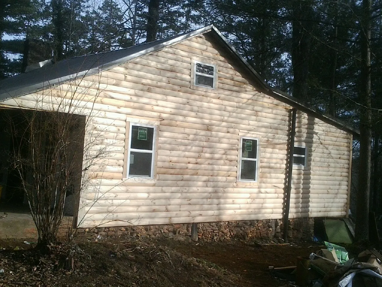 New log siding and dark metal roofing on a gable end in Ferris