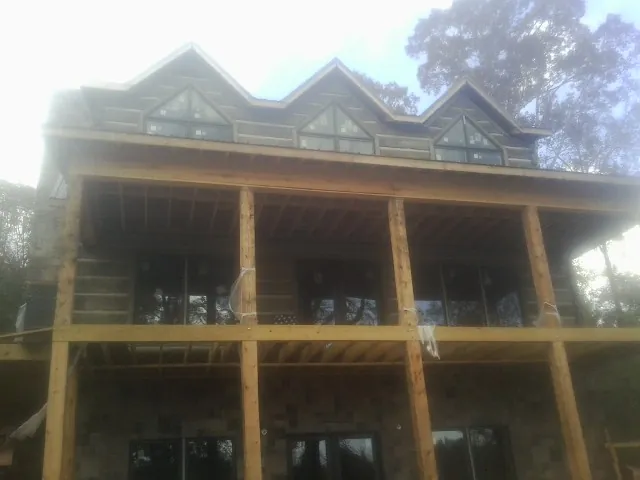 Dormers and porch framing on a large log home under construction — Roof Coating work by our crew in Ferris