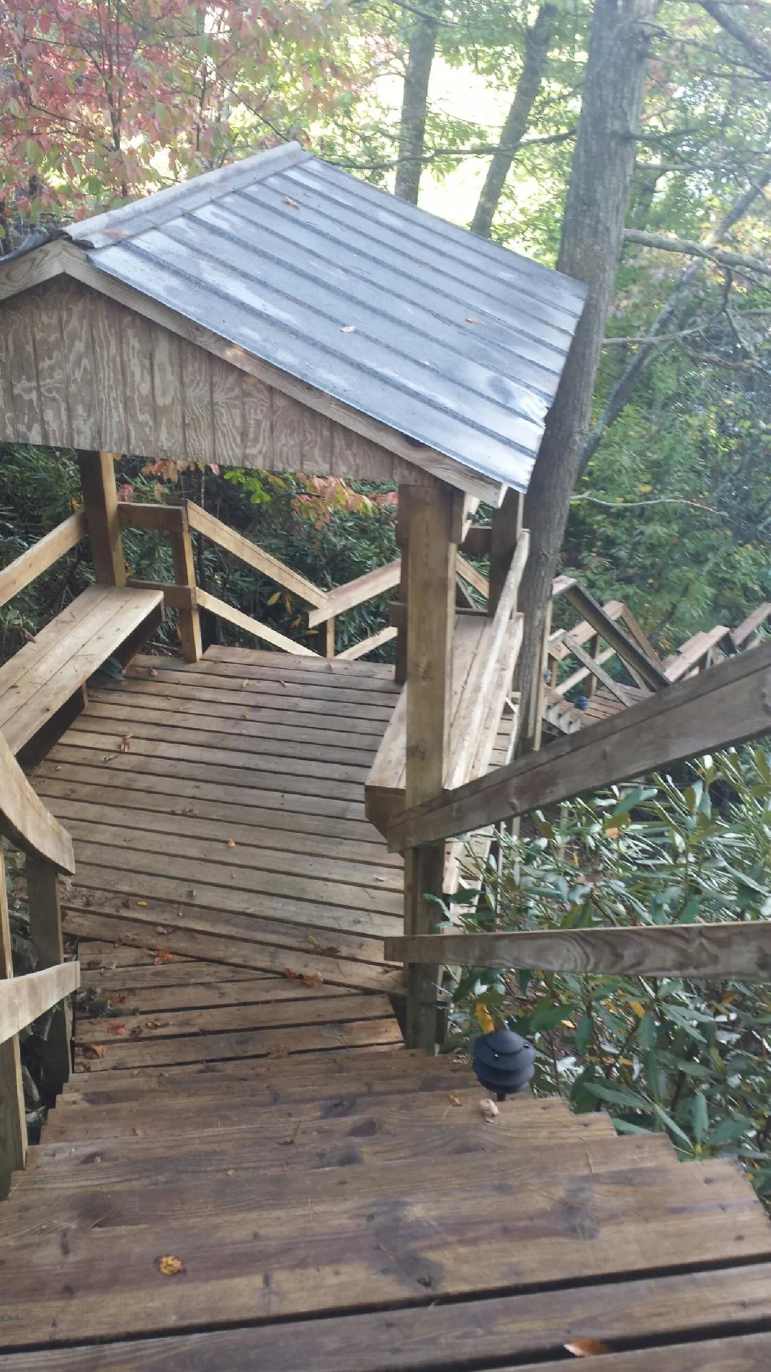 Metal roofed shelter over wooden steps on a wooded walkway — Skylight Repair & Installation work by our crew in Ferris