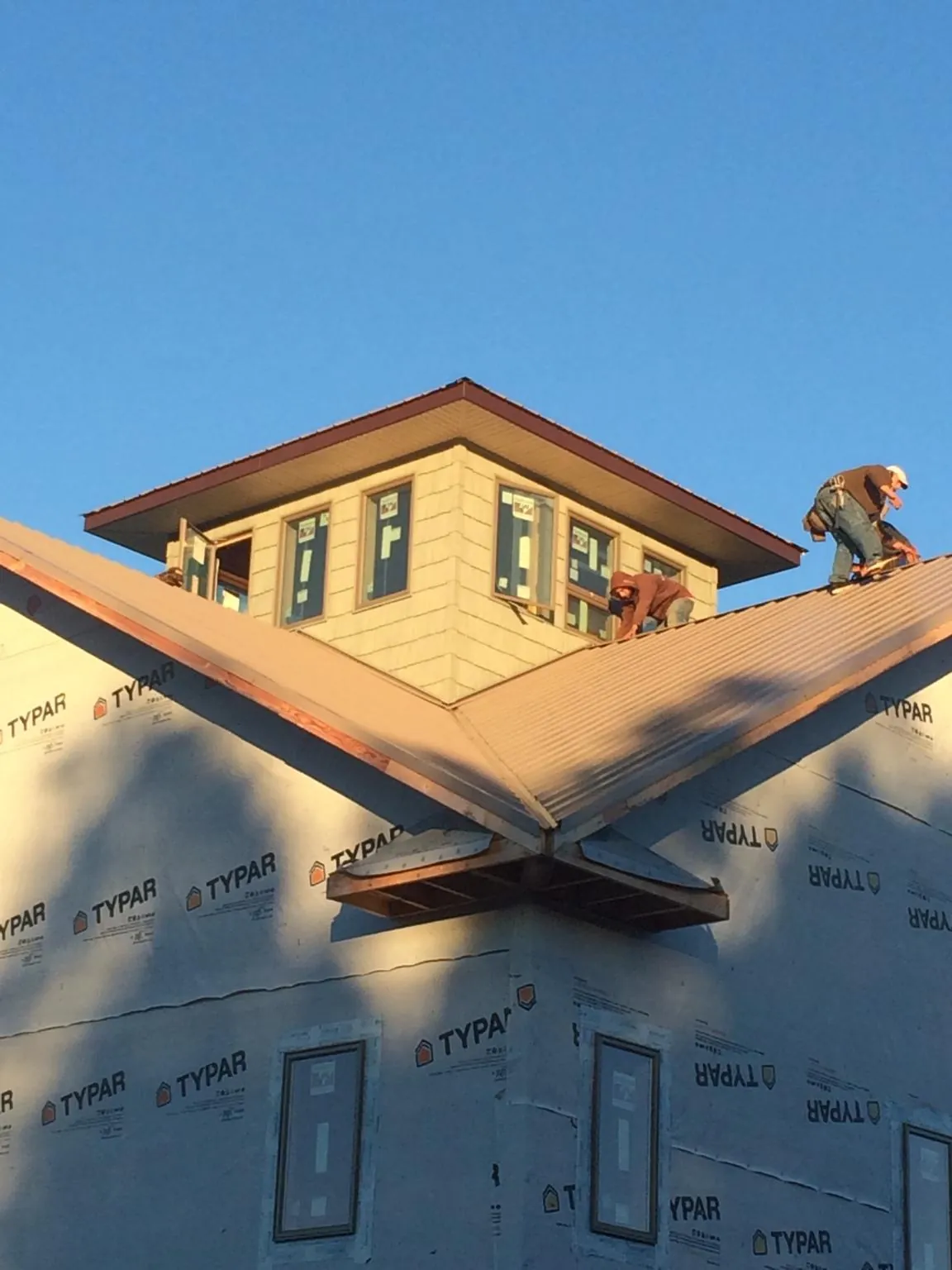 Roofers working around a rooftop cupola on a new metal roof at sunset — Roof Waterproofing in Ferris by Roofing Brothers